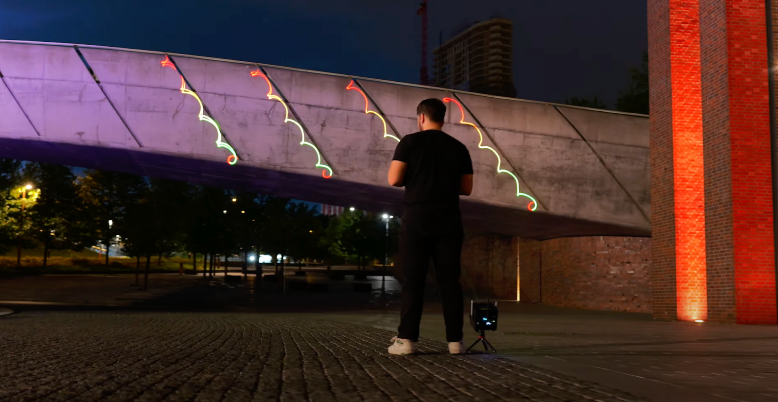 Person using the LaserCube laser show projector to show laser on a bridge